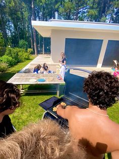 some people are sitting outside in the grass and grilling food on an outdoor grill