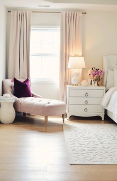 a bedroom with white furniture and pink curtains on the windowsill, along with a large rug