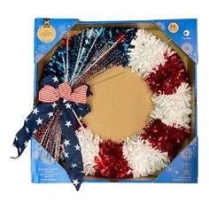 an american flag wreath with red, white and blue tinsels on it in a cardboard box