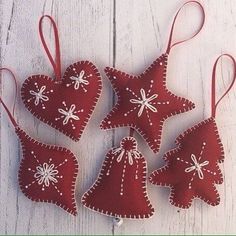 four red ornaments hanging from strings on a white wooden surface