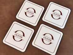 four coasters sitting on top of a brown leather surface with the word olver written across them