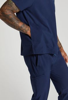 MADE FOR THE WAY YOU MOVE™: The Daniel 2 Pocket Scrub Top gives you the freedom to move. Made from EcoSoftMD™ fabric that breathes and stretches you'll stay cool, calm, and collected even into overtime. Functional Blue Cotton Activewear, Cotton Activewear With Pockets And 4-way Stretch, Navy Relaxed Fit Activewear For Sports, Navy Relaxed Fit Athleisure Activewear, Navy Relaxed Fit Activewear For Athleisure, Navy Cotton Athleisure Activewear, Cotton Athleisure Activewear With 4-way Stretch, Blue Cotton Activewear With Side Pockets, Blue Cotton Go-dry Activewear