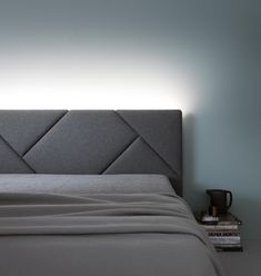 a bed with a gray headboard and nightstand next to it