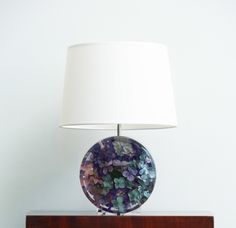 a lamp that is sitting on top of a wooden table next to a white wall