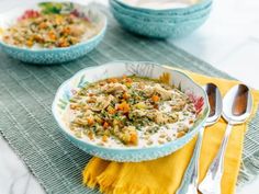 two bowls filled with food sitting on top of a table next to silverware and spoons