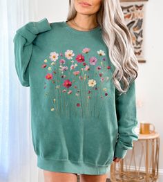 This gorgeous Comfort Colors sweatshirt features elegant, nature inspired Wildflowers design!  Luxurious comfort and style are what this unisex, garment-dyed sweatshirt is all about. It's made with 80% ring-spun cotton and 20% polyester and the fabric is 3-end garment-dyed, ring-spun, color-blast fleece with a 100% cotton face. Each sweatshirt comes with a relaxed fit, a rolled-forward shoulder, and a back neck patch.   .: 80% ring-spun cotton, 20% polyester .: Medium-heavy fabric (9.5 oz /yd² (322.1 g/m .: Relaxed fit .: Sewn in twill label .: OEKO-TEX certified low-impact dyes Key features: 1x1 Ribbed collar, cuffs and bottom hem - allows the sweatshirt to stretch as it's put on, afterwards it goes back to its original size, leaving a well-fitted garment. Back detail - the sweatshirt has Fall Cotton Sweater With Floral Print, Fall Cotton Floral Print Sweater, Cotton Floral Print Fall Sweater, Cotton Floral Print Sweater For Fall, Green Graphic Print Sweater For Spring, Green Cotton Sweater For Spring, Spring Green Cotton Sweater, Casual Long Sleeve Tops With Plant Print, Spring Graphic Print Relaxed Sweater