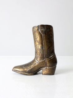 a pair of gold cowboy boots sitting on top of a white table