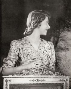 an old black and white photo of a woman standing in front of a framed photograph