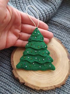 a small green christmas tree ornament sitting on top of a piece of wood