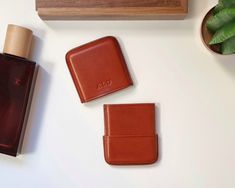 three pieces of leather sitting on top of a table next to a wooden box and plant