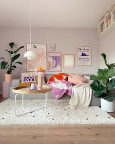 a living room filled with furniture and lots of plants on top of a white rug