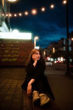 a woman sitting on a bench at night