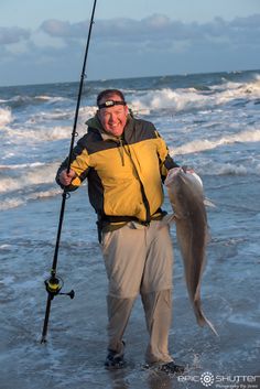 a man holding a fish while standing in the ocean