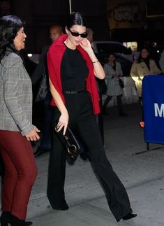 a woman in black and red is walking down the street