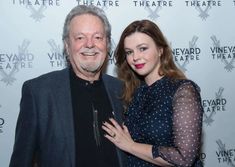 an older man standing next to a young woman on the red carpet at a theatre