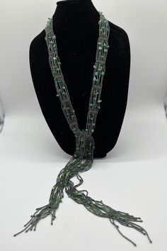 a necklace on a mannequin with green beads and chains hanging from it's neck