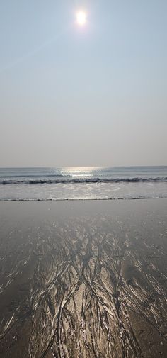 the sun is shining over the water and sand at the beach with waves coming in