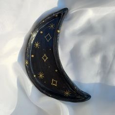 a black and gold crescent shaped object laying on a white sheet with stars all over it