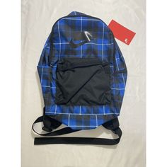 a blue and black plaid backpack sitting on top of a white bed next to a red tag