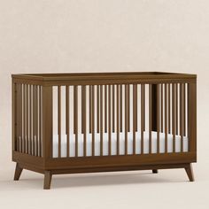 a wooden crib with white sheets on the bottom, and side rails to the sides