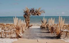 an outdoor ceremony set up on the beach with chairs and palm trees in front of it