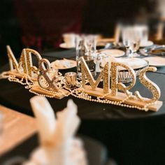 the table is set for a wedding reception with mr and mrs spelled in gold letters