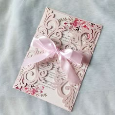 a wedding card with a pink bow on it sitting on top of a blue blanket