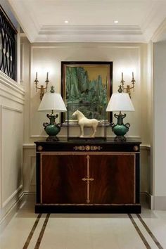 a horse statue sitting on top of a table next to two lamps and a painting