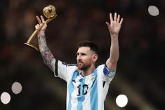 a man holding up a golden trophy in his right hand while wearing a blue and white shirt