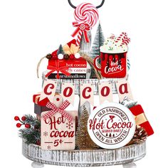 a christmas gift basket filled with hot cocoa, candy and other holiday treats on top of a white platter