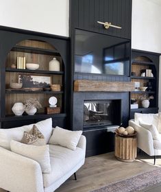 a white couch sitting in front of a black book shelf filled with vases and other items