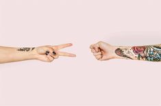 two people with tattoos on their arms pointing at each other's fingers in opposite directions