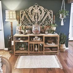 a living room with an ornate headboard and wooden shelves filled with pots and plants