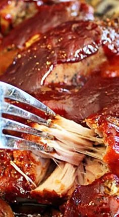 a fork is stuck into some meat in the bbq sauce that's ready to be eaten