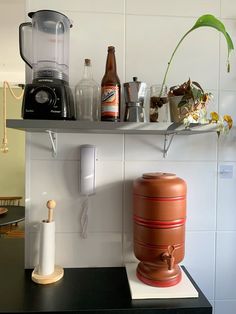 a kitchen counter topped with an orange vase next to a blender and other items