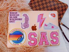 an assortment of stickers on top of a pink laptop computer case next to a purse