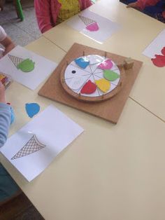 children are sitting at a table making paper crafts with scissors and glue on the surface