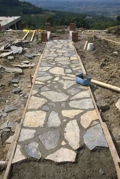 a stone walkway being built in the middle of a field with construction materials around it