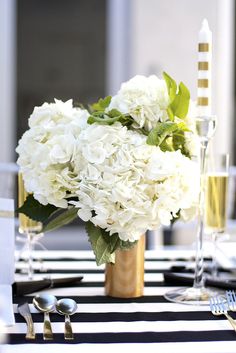 a vase filled with white flowers sitting on top of a black and white table cloth