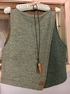 a sweater vest hanging on a clothes rack in front of a window with an open door