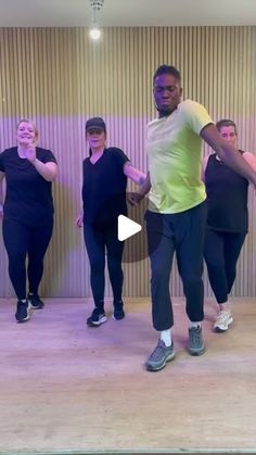 a group of people standing on top of a wooden floor in front of a wall