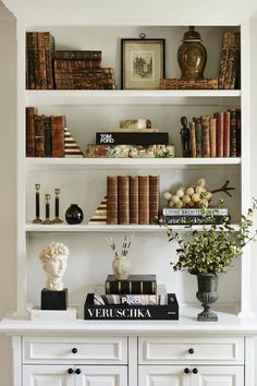 a bookshelf filled with lots of books next to a vase and other items