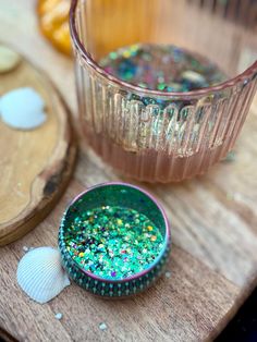 there is a bowl with some glitter on it next to a glass and other items