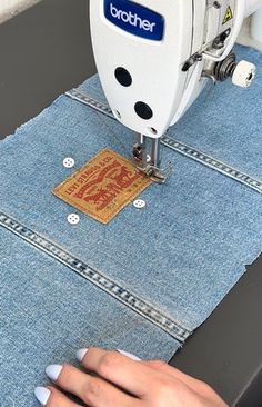 a woman using a sewing machine to sew jeans on top of a piece of denim