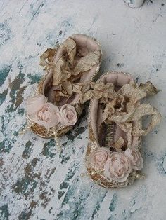 two baby shoes with flowers on them are sitting on the ground next to an old door