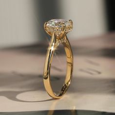 a yellow gold engagement ring with two diamonds on the top and bottom, sitting on a piece of paper