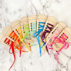 six pairs of wooden shoe laces on marble counter top with colorful ribbon tied around them