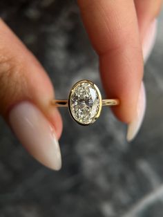 a woman's hand holding an engagement ring with a diamond in the center, on top of her finger