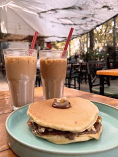 two glasses of chocolate milkshake and pancakes on a table