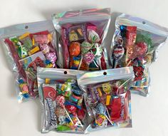 several bags filled with assorted candy on top of a white table next to each other